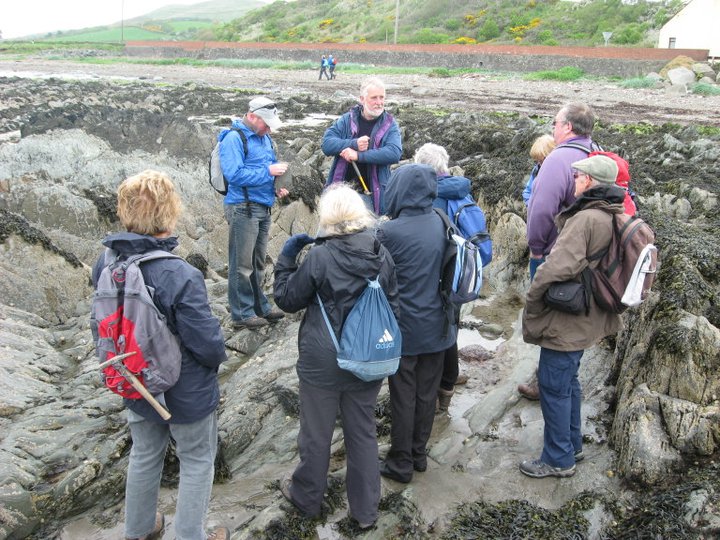 Group of people standing on a rocky shore.