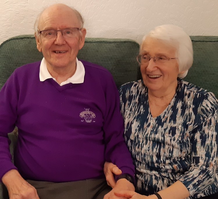 Man and woman sitting on a sofa holding hands
