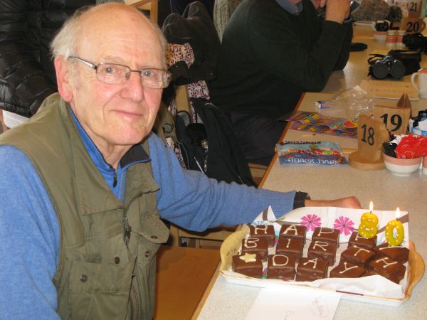Man sitting beside a table with an 80th birthday cake