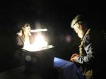 Two people looking at a moth trap with a bright light