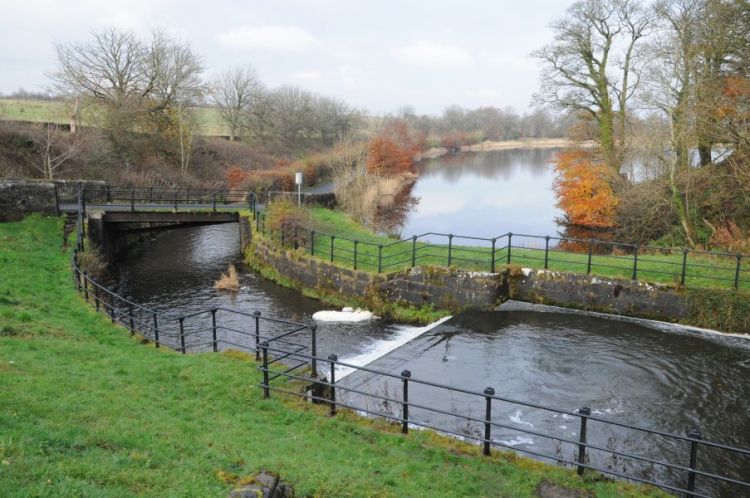 Dam and lade with fencing and footbridge and trees with autumn russet colours